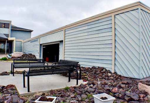 A bench is in front of a building with a blue wall.