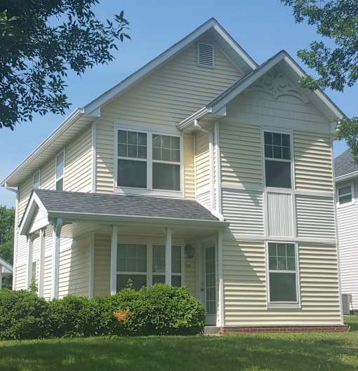 A white house with a grey roof and a small porch.