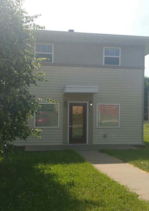 A house with a grey siding and a red car in the driveway.