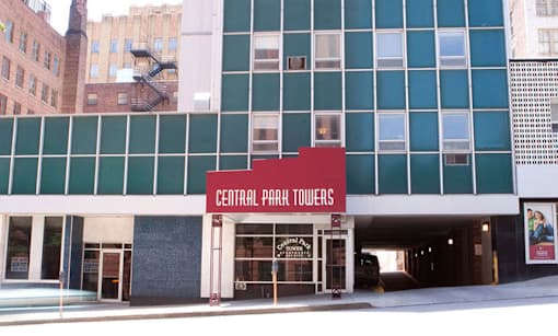 The Central Park Towers building is a large, modern structure with a red and white sign on the front.