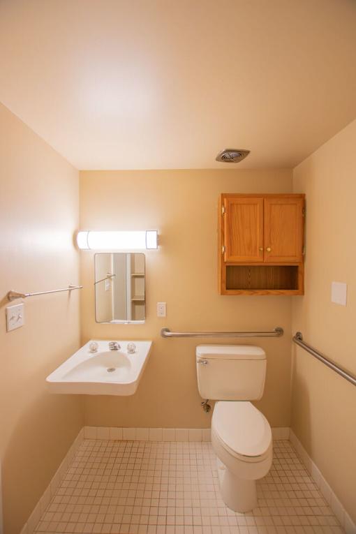 A bathroom with a toilet, sink, and mirror.