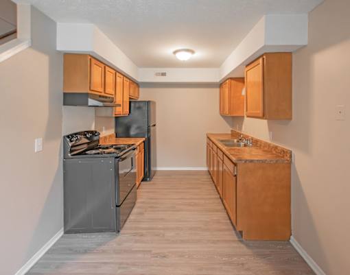 A kitchen with wooden cabinets and a black refrigerator.