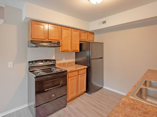 A kitchen with a stove, refrigerator, and cabinets.