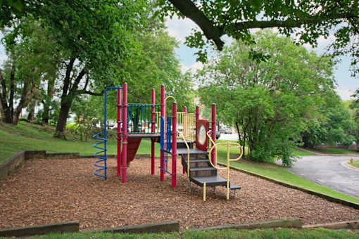 A playground with a red and blue swing set.
