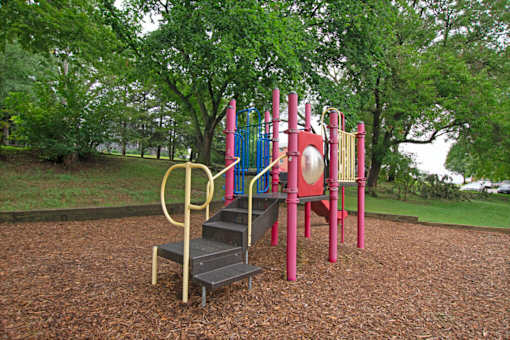 A playground with a slide, swings, and a seesaw.