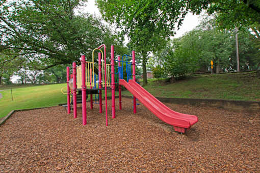 A playground with a red slide and a yellow railing.