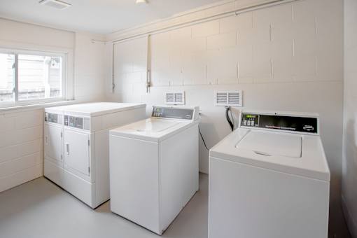 A laundry room with a washer, dryer, and ironing board.