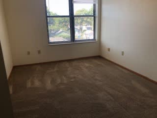 A room with a carpeted floor and a window.