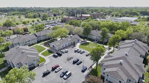 A parking lot in front of a building surrounded by trees.