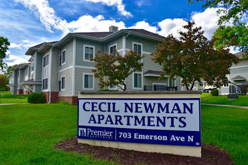 A sign for Cecil Newman Apartments in front of a building.