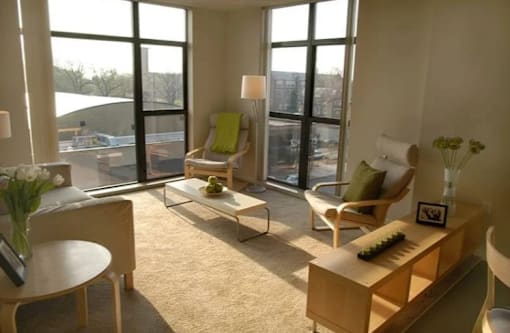A sunny room with a piano, chairs, and a table.
