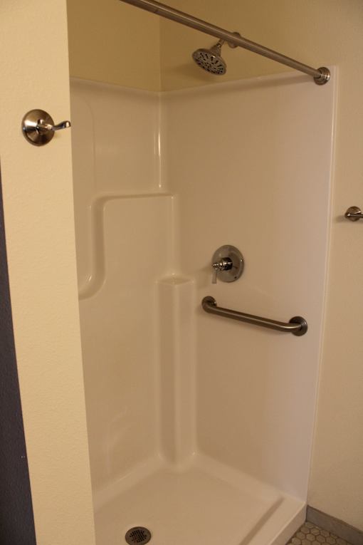 A white bathtub with a shower head and hand held shower.