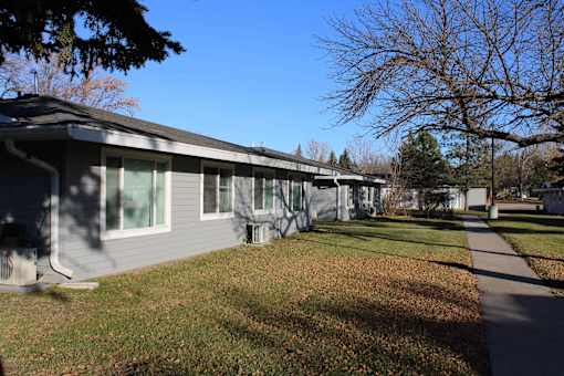 A grey building with a tree in front of it.