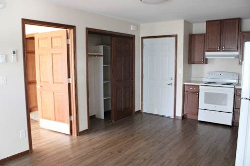 A kitchen with white appliances and wooden floors.