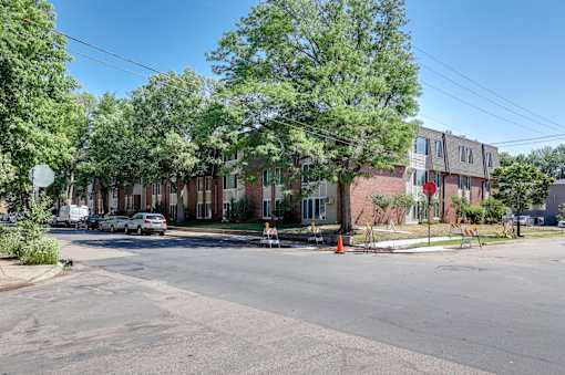 A street view of a residential area with apartment buildings and parked cars.