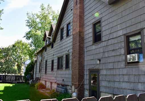 A house with a red brick chimney and a wooden fence.