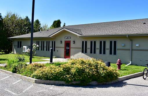 A small building with a red door and a fire hydrant in front.
