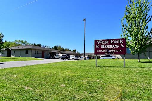 A sign for West Fork Homes stands in a grassy field.