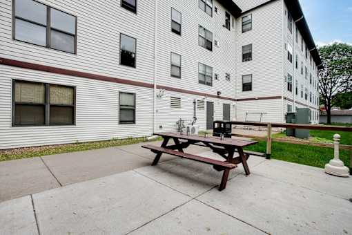 A white building with a red stripe and a picnic table in front.
