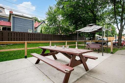 A picnic table with a red top is in the foreground of a park.