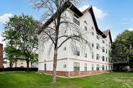 A white building with a red brick wall in front.