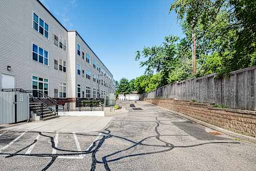 A parking lot in front of a building with a wooden fence on the right side.