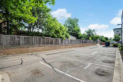 A parking lot with a wooden fence and trees in the background.