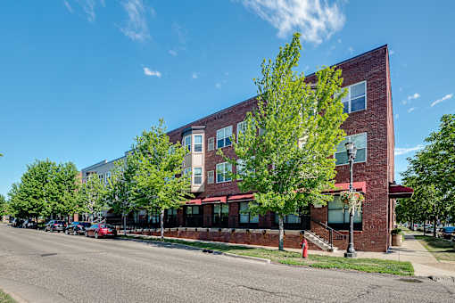 A red brick building with a green tree in front of it.