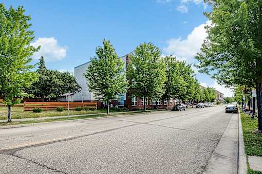 A tree-lined street with cars parked on the side.