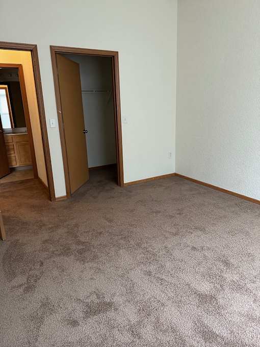 A room with a carpeted floor and two doors, one of which is open.