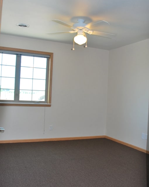 A room with a ceiling fan and a window.
