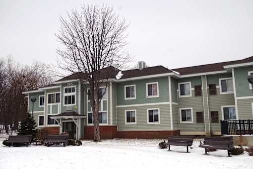 A large building with a green and brown exterior is surrounded by snow.