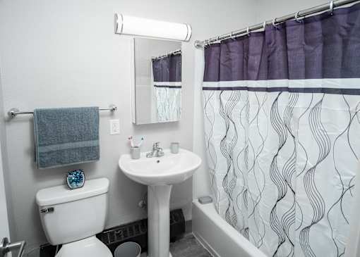A white toilet with a blue towel hangs on a wall next to a sink and a mirror.
