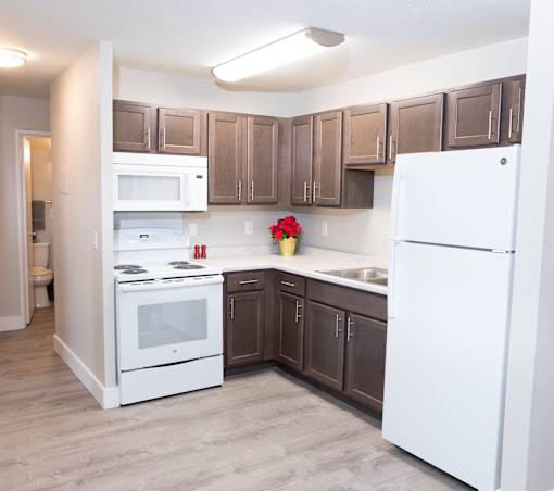 A kitchen with white appliances and brown cabinets.