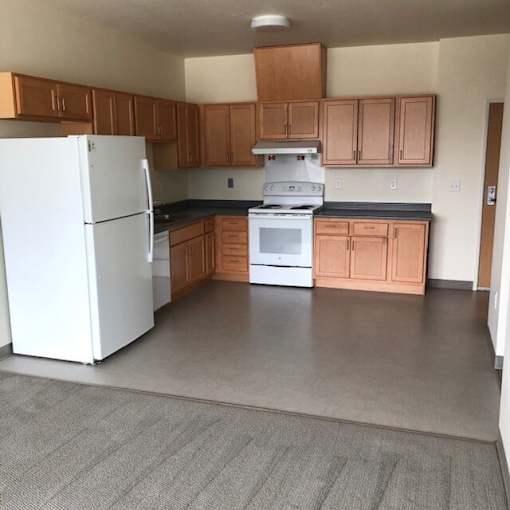 A white refrigerator is in a kitchen with wooden cabinets.