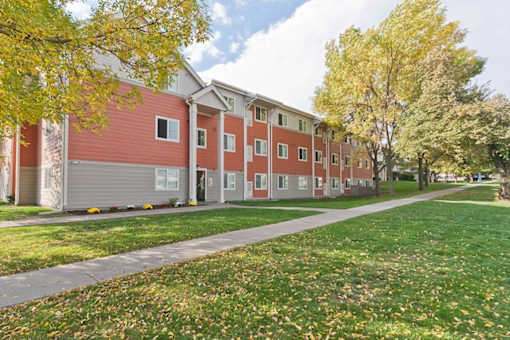 A red and beige building with a green lawn in front.