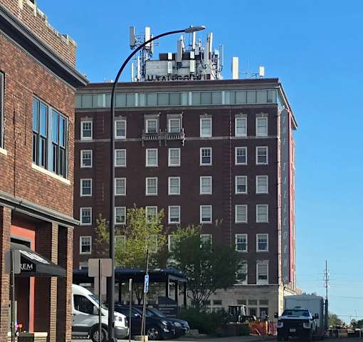 A tall red brick building with a white truck parked in front of it.