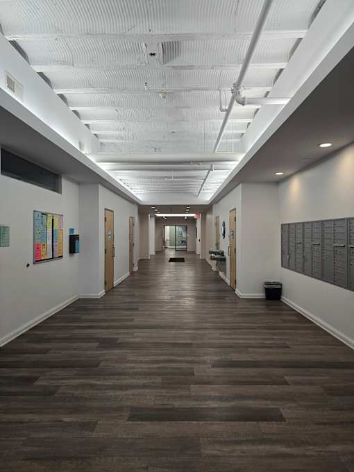 A long hallway with a white floor and a wall on the right side.