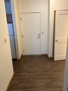 A hallway with a white door in the middle and a white door on the right.