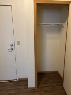 A white door is on the left of a room with a shelf.