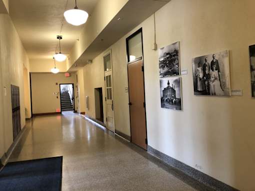 A hallway with a blue rug and pictures on the wall.