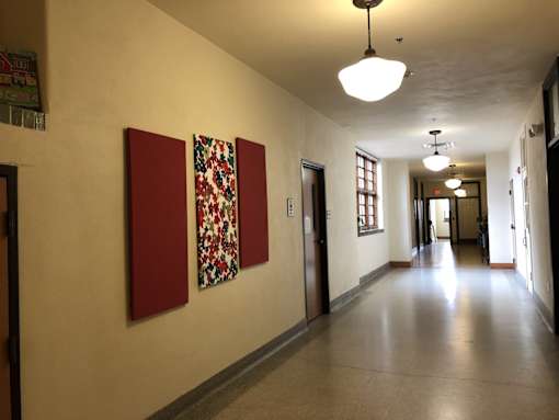 A long hallway with a light hanging from the ceiling and a picture on the wall.