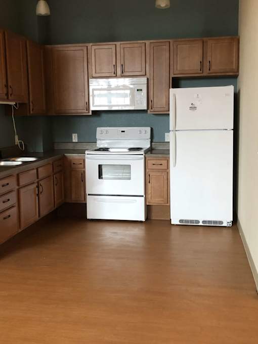 A kitchen with white appliances and wooden cabinets.