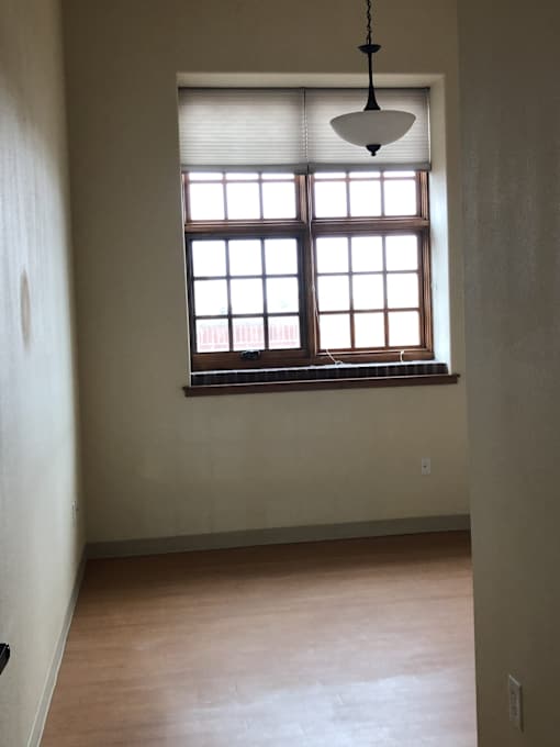 A room with a window and a hanging light fixture.