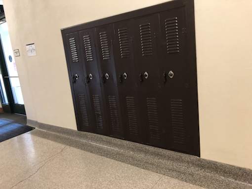 A row of four dark brown lockers with silver handles.