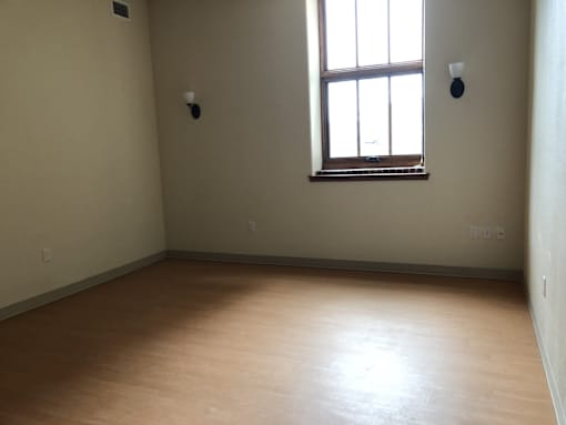 A room with a window and two smoke detectors on the wall.
