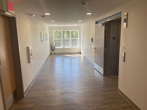 A long hallway with doors on both sides and a window in the distance.