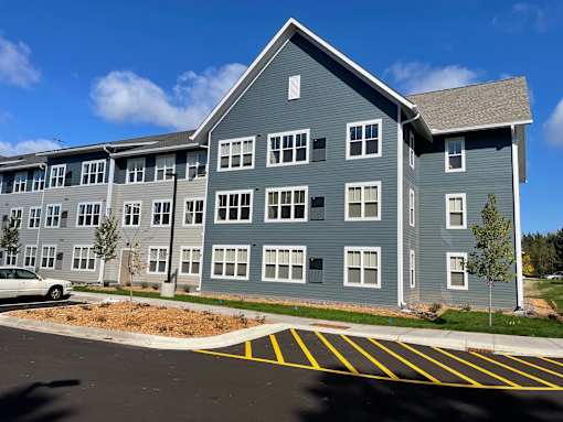 A large grey building with a parking lot in front.