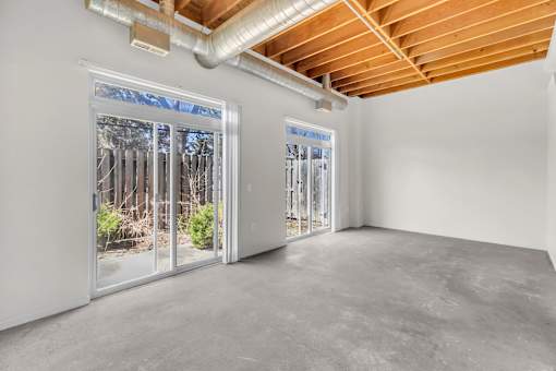 A room with a view of a forest through the windows.