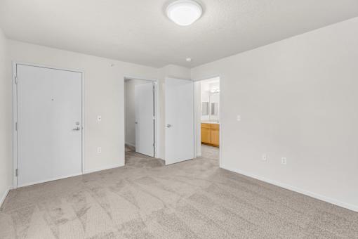 A room with white walls and a carpeted floor with three doors.